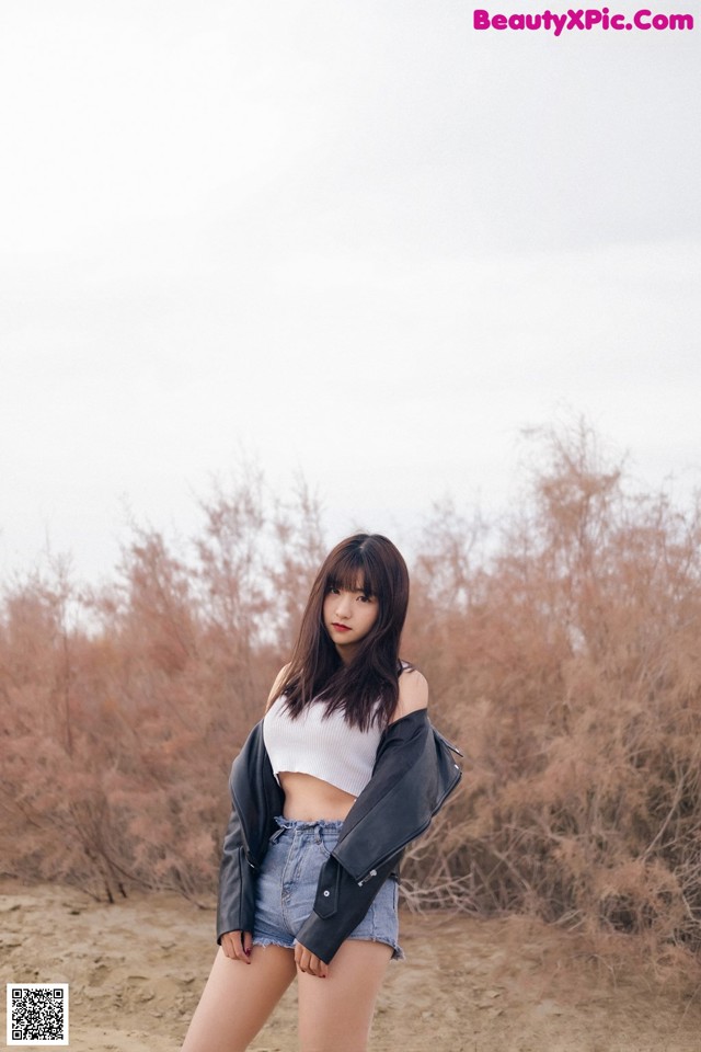 A woman standing in the middle of a dirt field.