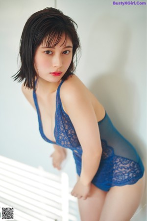 A woman in a blue lingerie laying on a red chair.