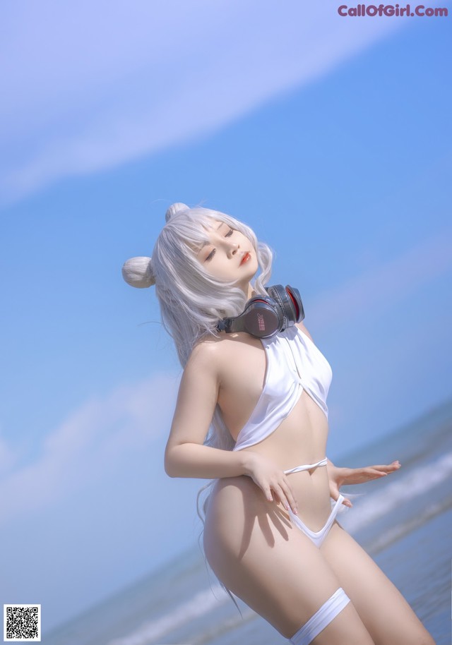 A woman in a white bikini standing on a beach.