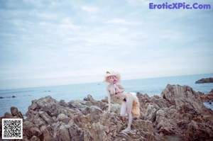 A woman in a bikini standing on a rocky beach.