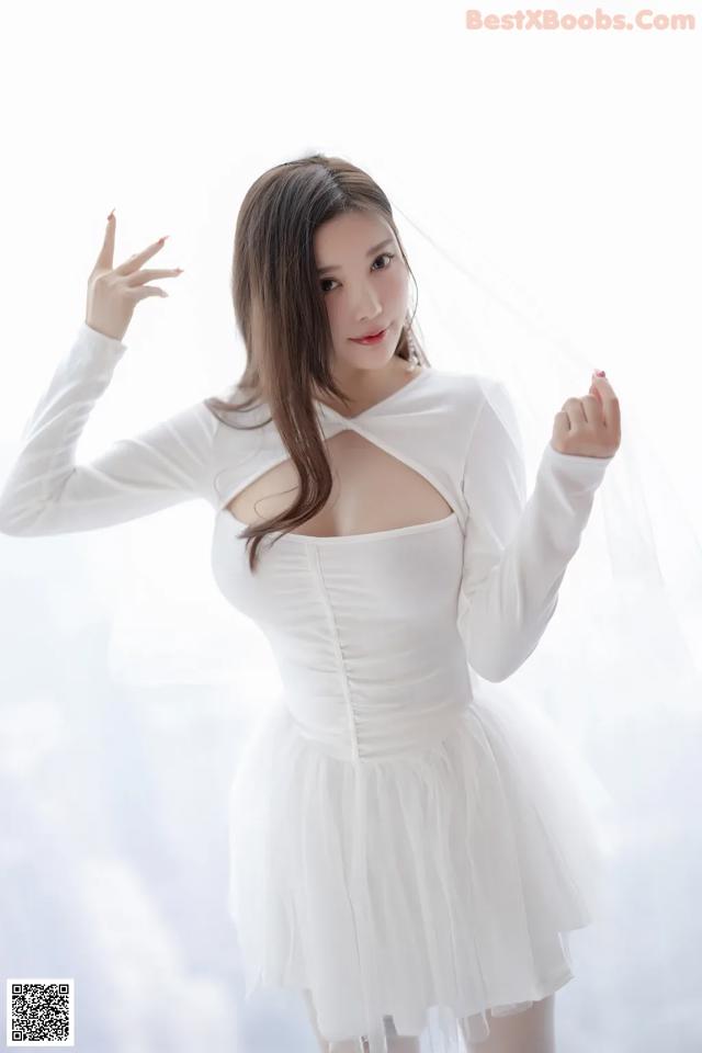 A woman in a white dress posing for a picture.