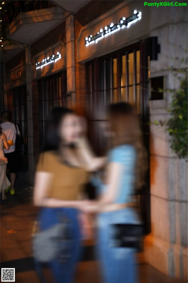 A couple of women standing in front of a building.