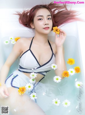 A woman in a bathtub with a flower in her hair.