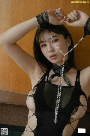 A woman in a black bodysuit and stockings sitting on the floor.