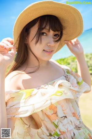 A woman wearing a straw hat looking out at the ocean.