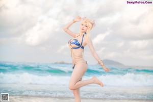 A woman in a bikini sitting on the beach.