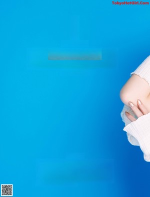 A woman sitting on a blue cube wearing a white shirt and green shorts.