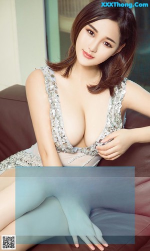A woman in a white dress sitting on a brown couch.