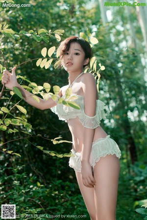 A woman in a white lingerie posing in the woods.