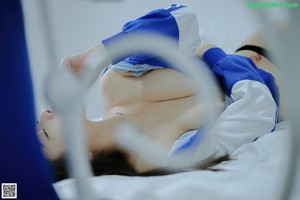 A woman in a blue and white outfit sitting on a bed.