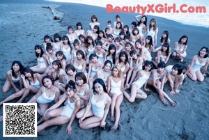 A group of women in white bathing suits standing on a beach.