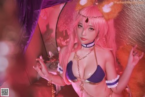 A woman with pink hair wearing a purple bikini.