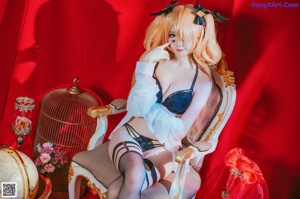 A woman in lingerie sitting on a chair with candles.