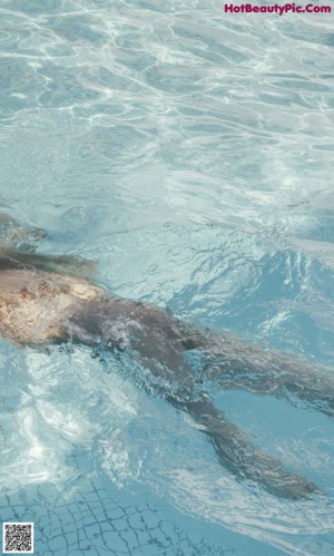 A woman in a swimming pool with her arms outstretched.