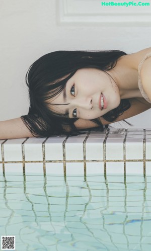 A woman sitting on the edge of a swimming pool.
