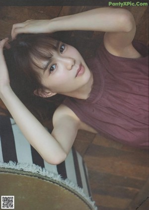 A young woman laying on top of a wooden table.