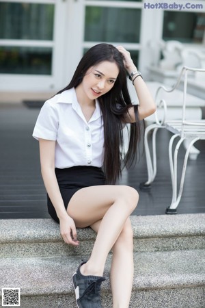 A woman in a white top and pink pants posing for a picture.