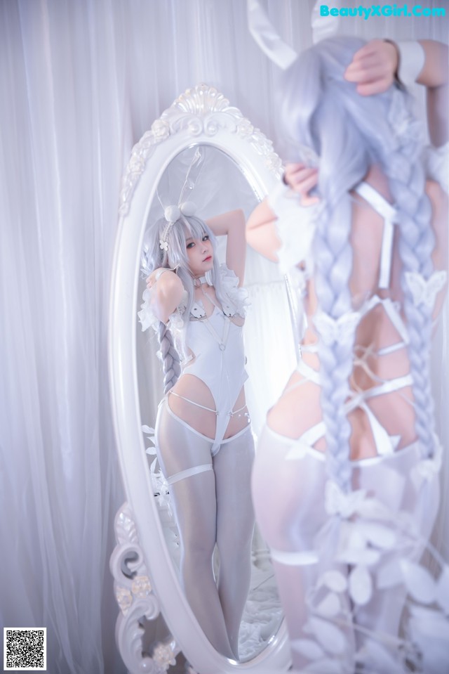 A woman in a white lingerie standing in front of a mirror.