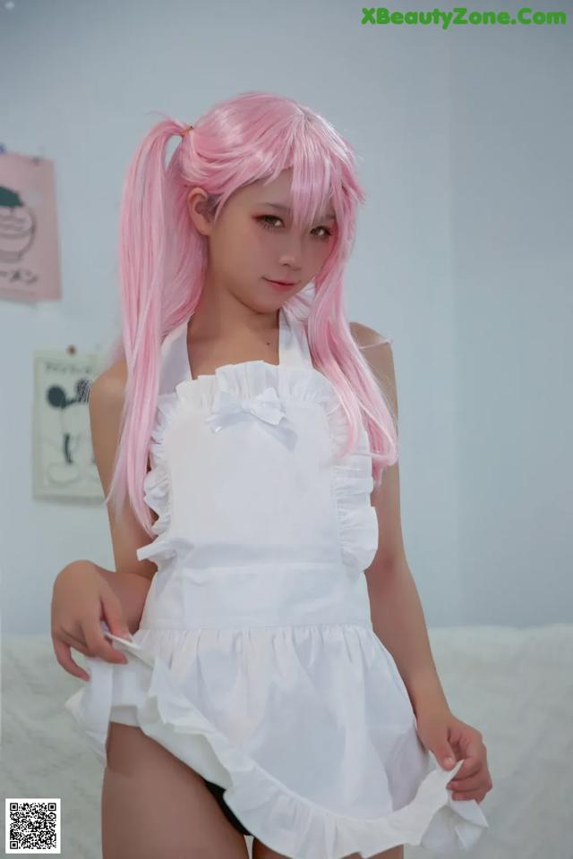 A woman with pink hair wearing a white dress.