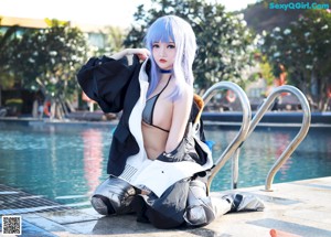 A woman with blue hair sitting next to a swimming pool.