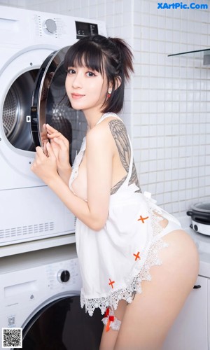 A woman in a white dress posing in a kitchen.