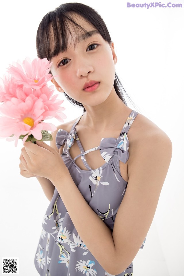 A woman holding a pink flower in her hand.