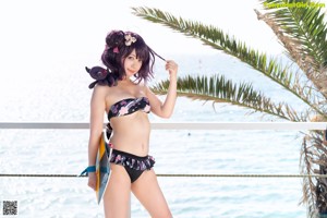 A woman in a bikini standing on a rock by the ocean.