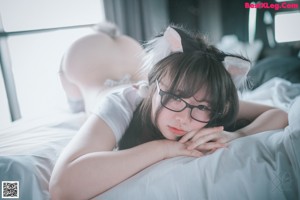 A woman in a cat costume is sitting on a bed.