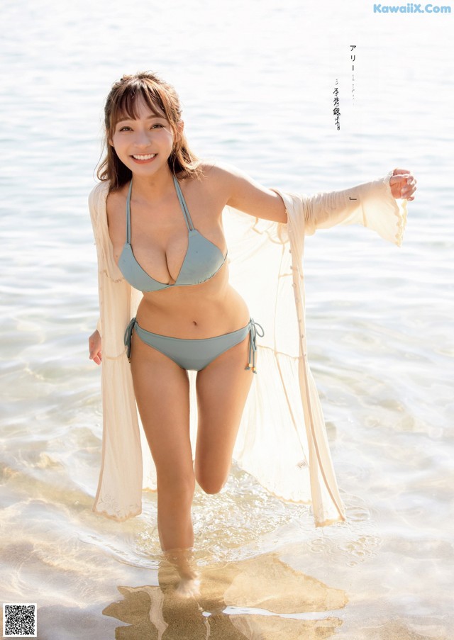 A woman in a blue bikini standing in the water.