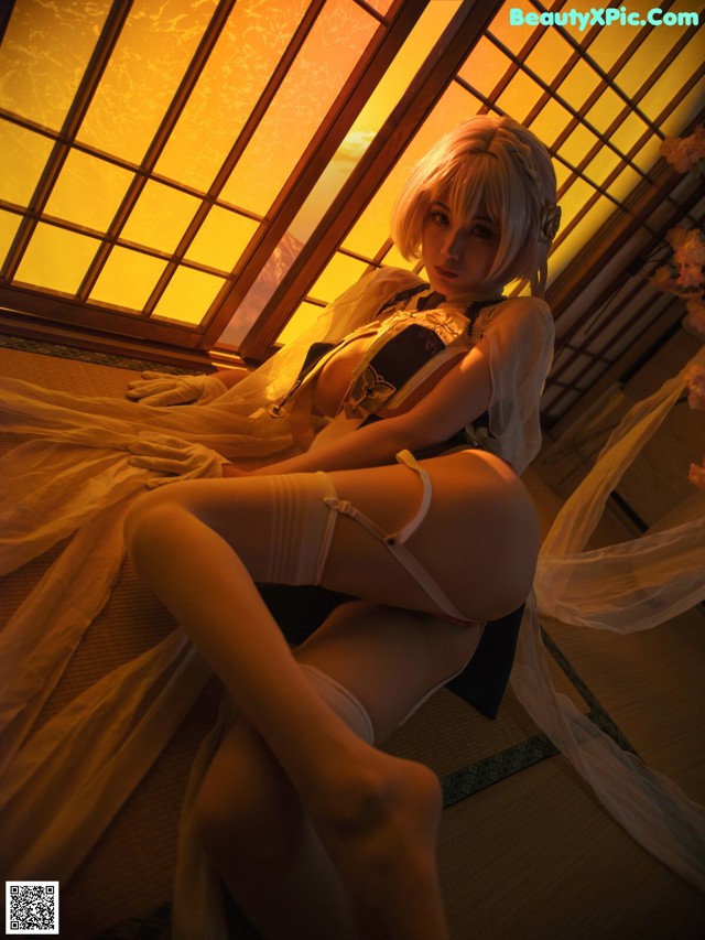 A woman in lingerie sitting on a bed in front of a window.