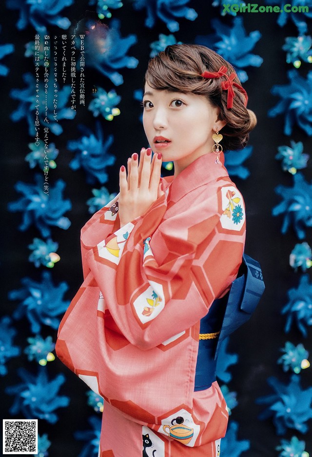 A woman in a red kimono standing in front of blue flowers.